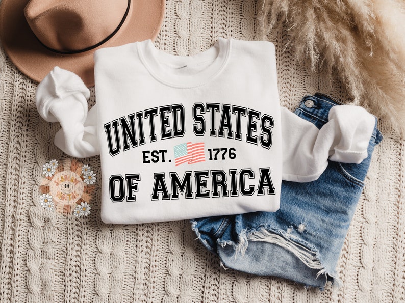 May include: White sweatshirt with a black graphic that says "UNITED STATES EST. 1776 OF AMERICA" with a small American flag graphic.