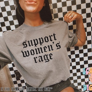 May include: A gray t-shirt with the text "Support Women's Rage" in black gothic lettering.