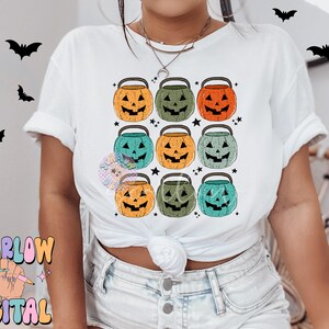 Puede incluir: Camiseta blanca con un patr&oacute;n de nueve cubos de calabaza de Halloween de colores. Los cubos est&aacute;n dispuestos en tres filas de tres. Cada cubo tiene un color diferente y una expresi&oacute;n facial diferente.