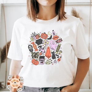 Peut inclure: T-shirt blanc avec un motif color&eacute; sur le th&egrave;me d'Halloween repr&eacute;sentant des fant&ocirc;mes, des chauves-souris, des citrouilles, des bonbons et le texte "Trick or Treat" et "Boo!"