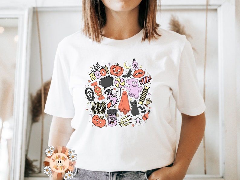 Peut inclure: T-shirt blanc avec un motif color&eacute; sur le th&egrave;me d'Halloween repr&eacute;sentant des fant&ocirc;mes, des chauves-souris, des citrouilles, des bonbons et le texte "Trick or Treat" et "Boo!"