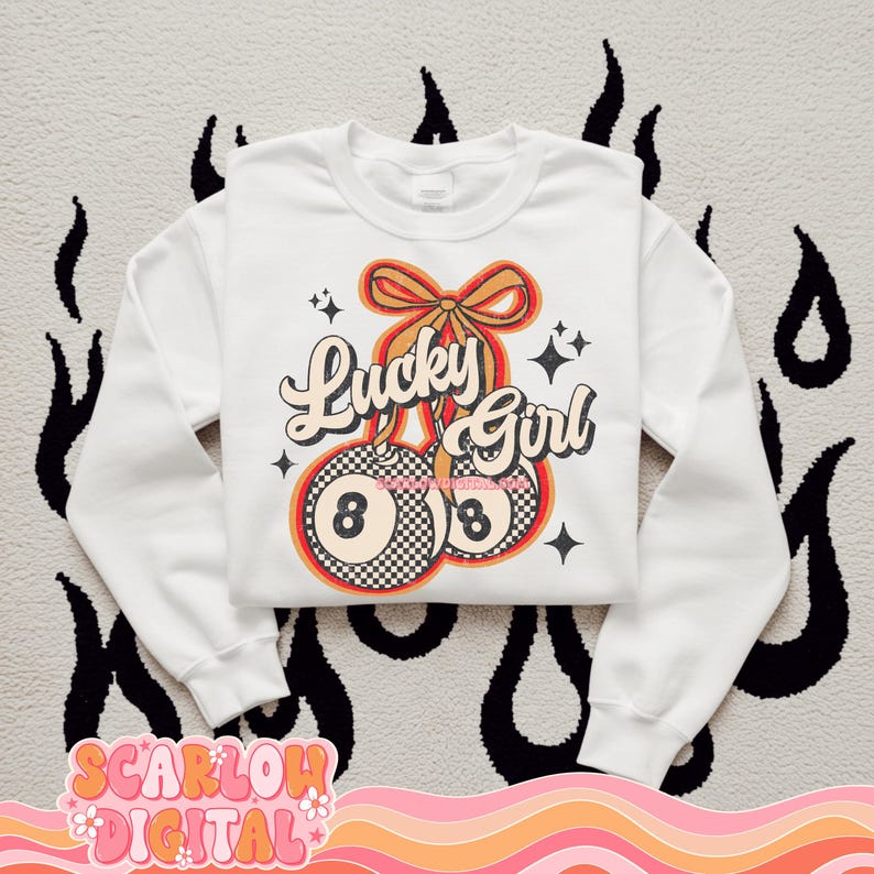 May include: White sweatshirt with a retro design featuring two 8-ball cherries with a red, orange, and yellow color scheme. The text "Lucky Girl" is written in a retro font above the cherries.