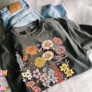 May include: A dark gray t-shirt with a floral print featuring a variety of colorful flowers, including pink, yellow, orange, and blue.