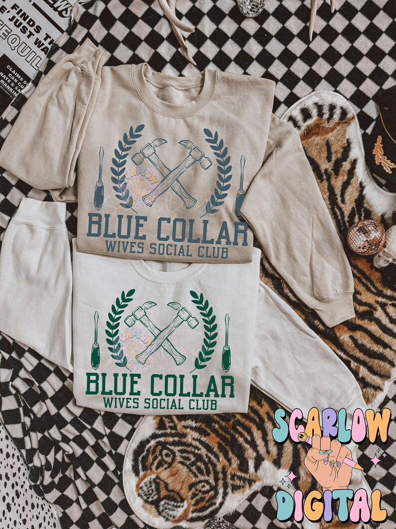 May include: A beige sweatshirt with a blue and green graphic design of crossed hammers and screwdrivers with a laurel wreath. The text "Blue Collar Wives Social Club" is printed below the graphic.