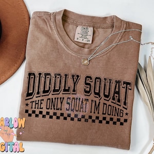 May include: A brown t-shirt with the text "Diddly Squat* The Only Squat I'm Doing*" in black lettering. The text is surrounded by a black and white checkered pattern.