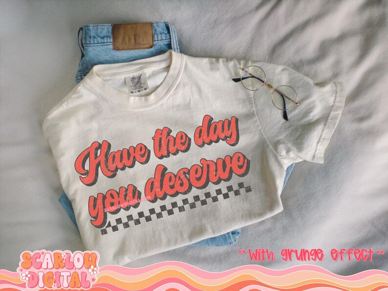 May include: White t-shirt with the text "Have the day you deserve" in red with a black and white checkered pattern underneath.