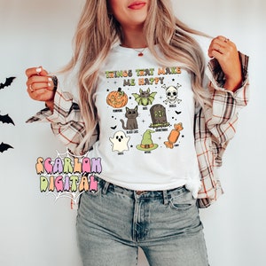 May include: White t-shirt with the text "Things that make me happy" and illustrations of Halloween icons, including pumpkins, bats, black cats, ghosts, witches, candy, and skulls.