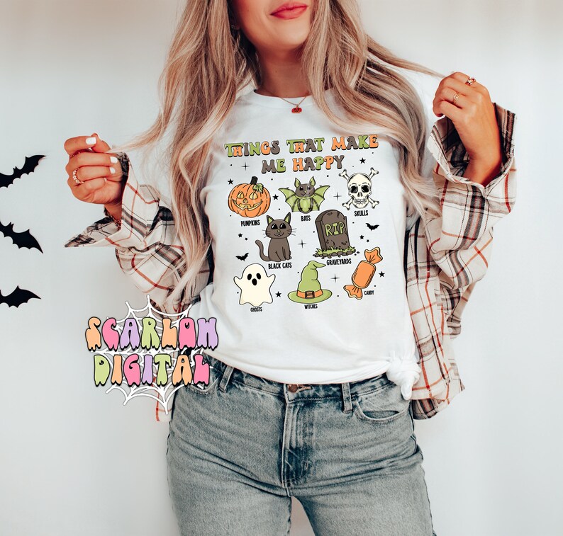 May include: White t-shirt with the text "Things that make me happy" and illustrations of Halloween icons, including pumpkins, bats, black cats, ghosts, witches, candy, and skulls.