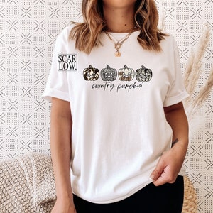 May include: White t-shirt with a graphic of four country-style pumpkins and the text "country pumpkin"