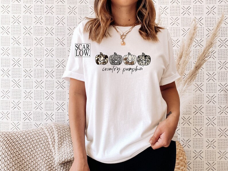 May include: White t-shirt with a graphic of four country-style pumpkins and the text "country pumpkin"