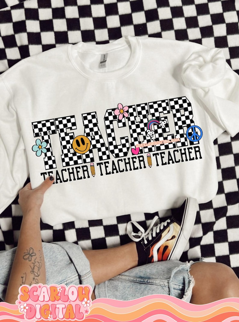 May include: White sweatshirt with the word "TEACHER" in black and white checkered letters. The letters are decorated with colorful flowers, a rainbow, a peace sign, a smiley face, and a pencil.