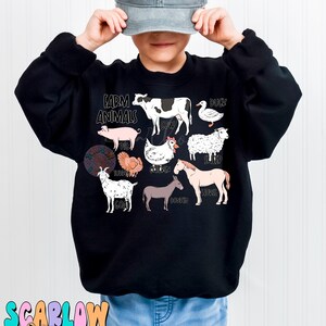 May include: A black sweatshirt with a graphic of farm animals and the text "Farm Animals" printed on the front. The graphic includes a cow, pig, duck, sheep, turkey, chicken, goat, donkey, and horse. The sweatshirt is being worn by a child wearing a gray baseball cap and blue jeans.