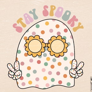 May include: A white ghost with colorful polka dots and sunglasses, wearing a peace sign on each hand. The text "STAY SPOOKY" is written in a rainbow arch above the ghost.