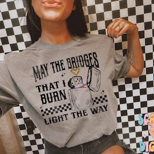 May include: A gray t-shirt with the text "May the bridges that I burn light the way" and a graphic of a lighter with a heart on it.