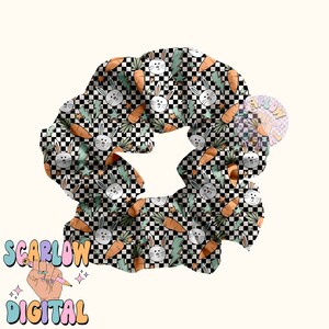 May include: A black and white checkered scrunchie with a pattern of green leaves, carrots, and white bunnies. The scrunchie is made of fabric and is designed to hold hair in place.