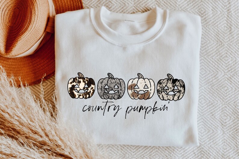 May include: White sweatshirt with a graphic of four cow print pumpkins with black outlines and the text "country pumpkin".