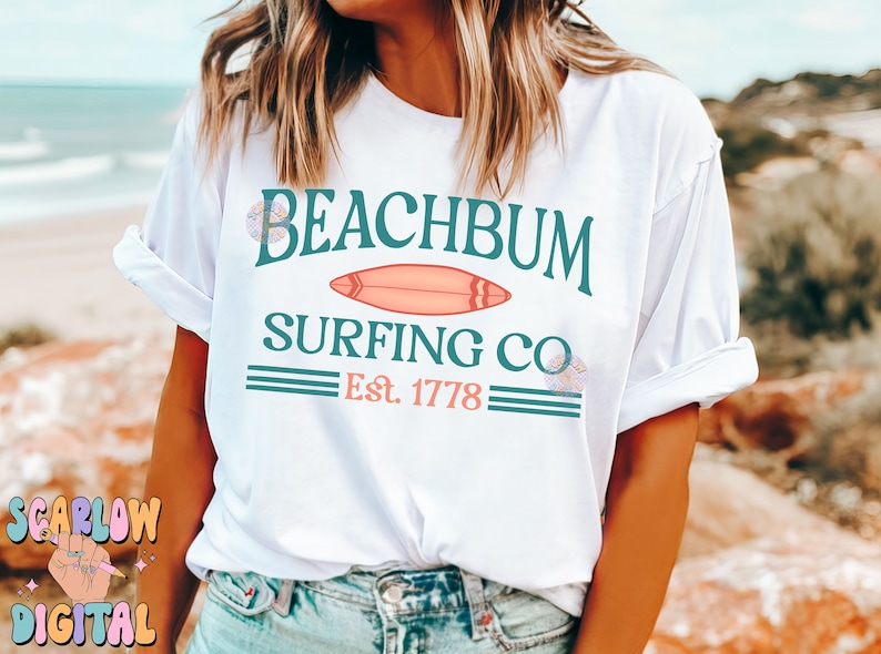 May include: White t-shirt with a teal and pink graphic design that says "Beachbum Surfing Co. Est. 1778".