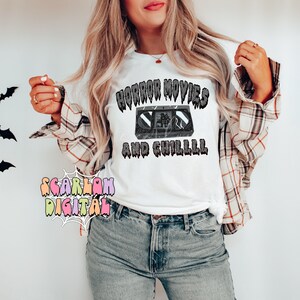 May include: White t-shirt with a black and white graphic of a VHS tape and the text "Horror Movies and Chilll" in a dripping font.