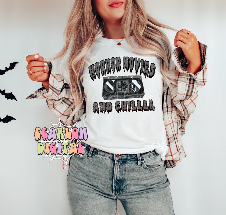May include: White t-shirt with a black and white graphic of a VHS tape and the text "Horror Movies and Chilll" in a dripping font.