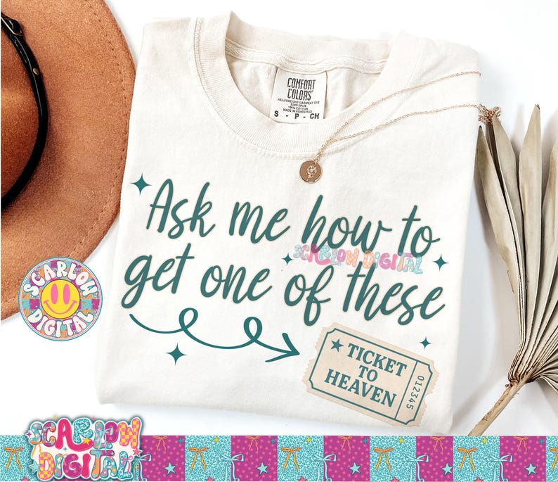 May include: Cream-colored t-shirt with the text "Ask me how to get one of these" in teal script. A "Ticket to Heaven" graphic is on the lower right. A gold necklace and a brown hat are also visible.