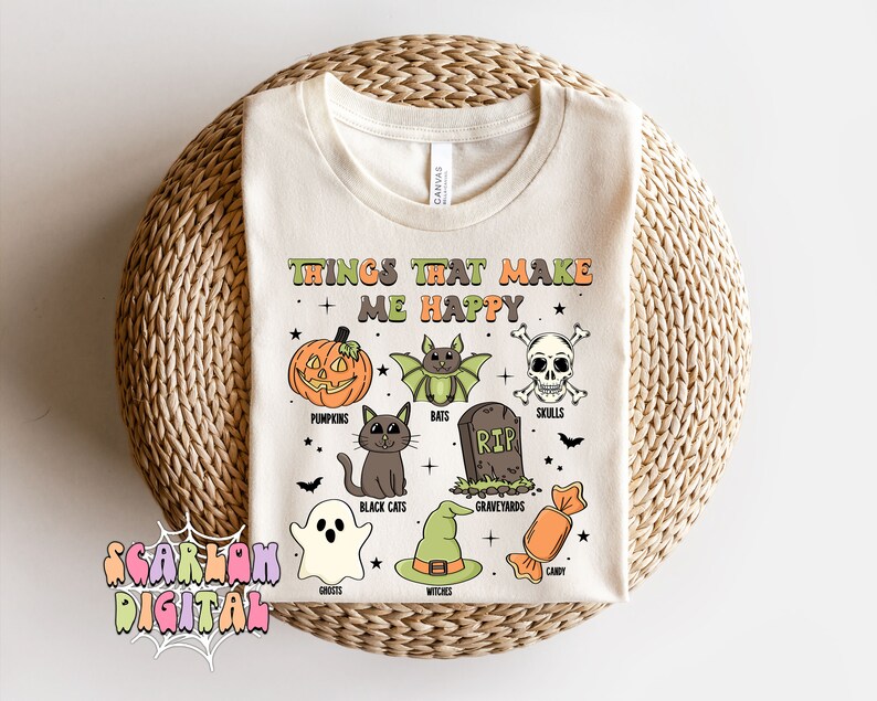 May include: A white t-shirt with the text "Things that make me happy" and a list of Halloween-themed items, including pumpkins, bats, skulls, black cats, graveyards, ghosts, witches, and candy.