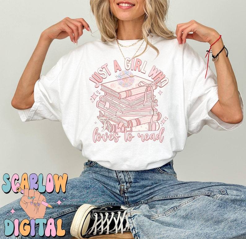 Puede incluir: Camiseta blanca con un gr&aacute;fico rosa que dice "Just a girl who loves to read" y presenta una pila de libros con un dise&ntilde;o floral.