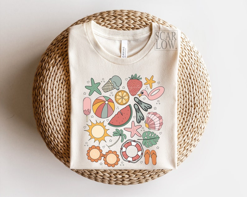 K&ouml;nnte beinhalten: Ein cremefarbenes T-Shirt mit einem Kreisdesign, das verschiedene sommerliche Illustrationen zeigt, darunter eine Wassermelone, ein Eis am Stiel, ein Strandball, Flip-Flops, ein Seestern, eine Palme, eine Muschel, ein Rettungsring und ein Flamingo.