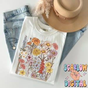 May include: White t-shirt with a floral print featuring a variety of flowers in shades of pink, yellow, orange, and blue. The text "SCARLOW DIGITAL" is visible in the bottom right corner of the image.