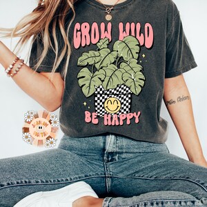 May include: A gray t-shirt with a graphic of a potted plant with the text "Grow Wild" and "Be Happy".
