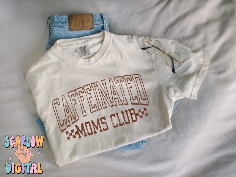 K&ouml;nnte beinhalten: Ein wei&szlig;es T-Shirt mit braunem Text, der "CAFFEINATED MOMS CLUB" lautet, mit einem karierten Muster unter dem Text.