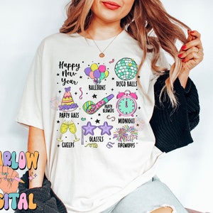 Może przedstawiać: Biały T-shirt z kolorowym wzorem graficznym przedstawiającym ikony sylwestrowe, w tym czapki imprezowe, balony, kule dyskotekowe, dmuchawy imprezowe, szklanki, fajerwerki i tekst "Happy New Year".