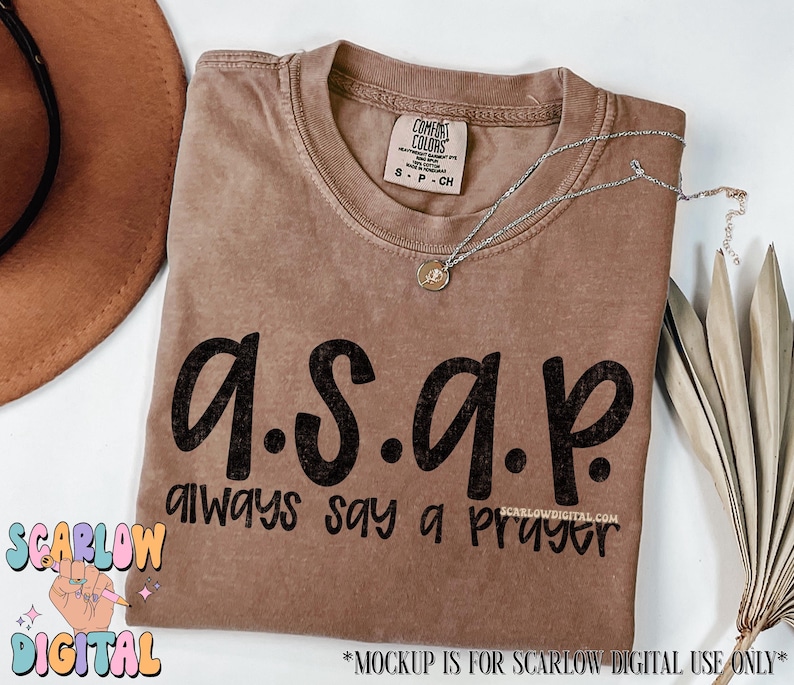 May include: A brown t-shirt with the text "a.s.a.p. always say a prayer" printed on it in black.