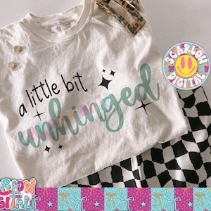 K&ouml;nnte beinhalten: Ein cremefarbenes T-Shirt mit dem Schriftzug "a little bit unhinged" in schwarzer und teal-farbener Schrift, akzentuiert mit Sternen. Das Shirt wird mit einer schwarz-wei&szlig; karierten Hose und einem Haaraccessoire mit Leopardenmuster kombiniert.