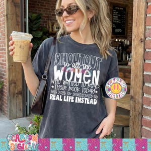 May include: Dark gray t-shirt with the text "SHOUTOUT to all the WOMEN who wanted to read THEIR BOOK TODAY but had to participate in REAL LIFE INSTEAD." The shirt also has a colorful smiley face sticker.