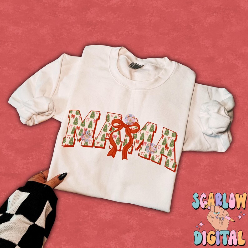 May include: White t-shirt with the word "MAMA" printed in red outlined letters. The letters are filled with a pattern of green Christmas trees and red bows.
