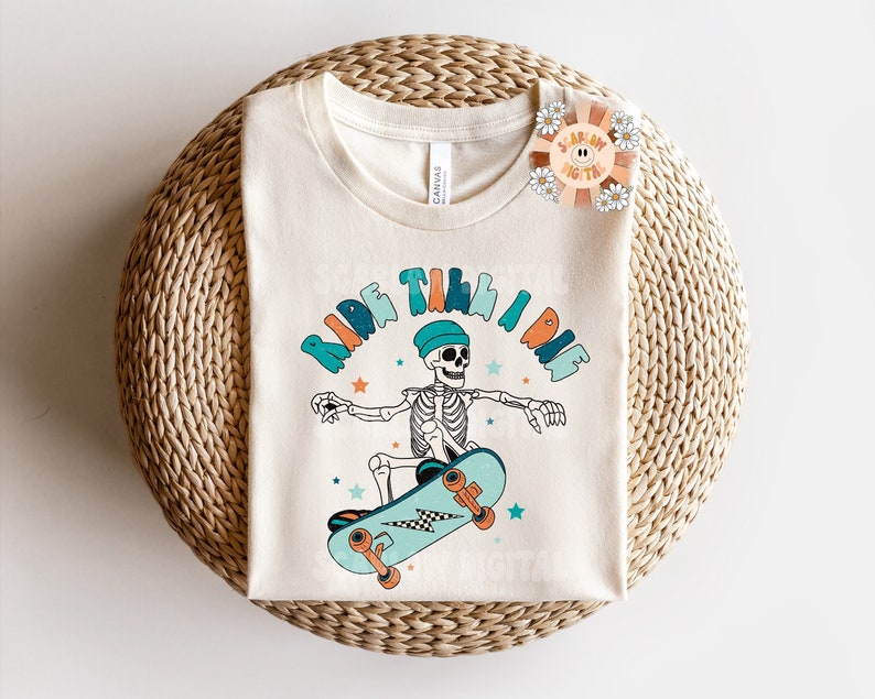 K&ouml;nnte beinhalten: Ein wei&szlig;es T-Shirt mit einem Grafikdruck eines Skeletts, das Skateboard f&auml;hrt, und dem Text "Ride Till I Die".
