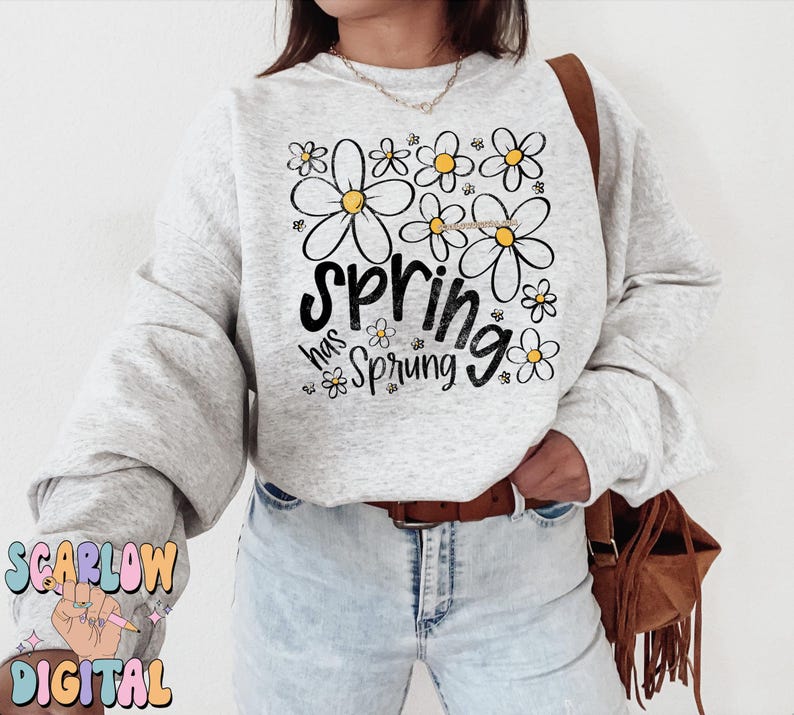 Puede incluir: Sudadera gris claro con la frase "spring has sprung" en letras negras y un dise&ntilde;o floral. Las flores son blancas con centros amarillos. La sudadera tiene mangas largas y cuello redondo.