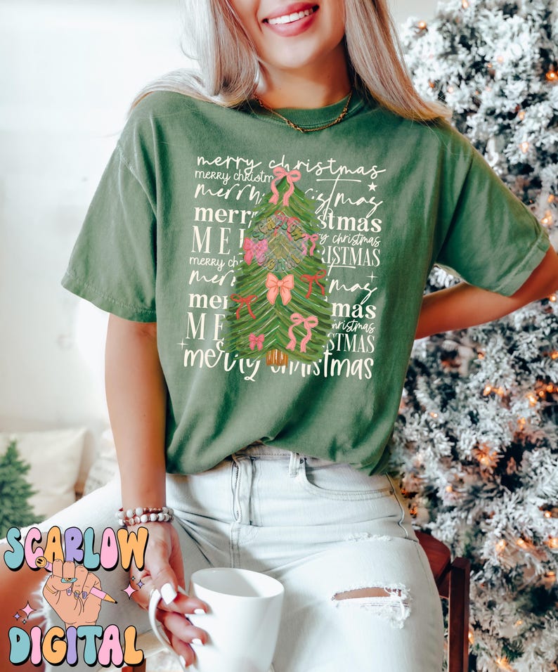 May include: A green t-shirt with a Christmas tree design made of the words "merry christmas" repeated in different sizes and styles. The tree is decorated with pink bows.