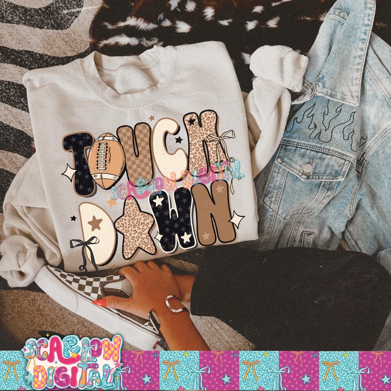 May include: A cream-colored sweatshirt with the words "TOUCH DOWN" in a mix of fonts and patterns, including a football graphic and star accents. A denim jacket and checkered sneakers are also visible.