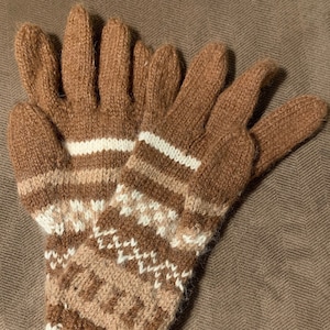 May include: A pair of brown knitted gloves with a white and brown geometric pattern. The gloves are made of a soft, warm material and are perfect for keeping your hands warm in the winter.
