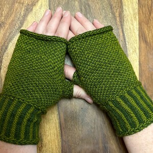 May include: A pair of green fingerless gloves with a striped cuff. The gloves are knitted and have a textured pattern.
