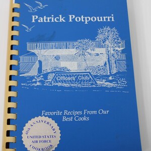 May include: A blue spiral-bound cookbook titled Patrick Potpourri with a white line drawing of a building and palm trees. The cover features the text Favorite Recipes From Our Best Cooks and a silver 40th Anniversary United States Air Force seal.