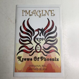 May include: A rectangular program booklet with a white cover featuring the text IMAGINE at the top. A central graphic depicts a stylized phoenix with red and black wings, the letters KOP, and the text Est. 2009. Below is Krewe Of Phoenix, Inaugural Ball, January 23, 2010.