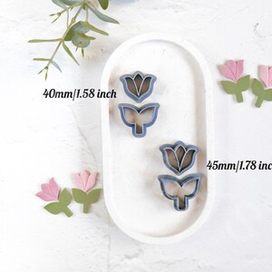 May include: Two metal cookie cutters shaped like tulips. The larger cutter is 1.78 inches tall and the smaller cutter is 1.58 inches tall.
