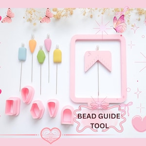May include: A pink bead guide tool set with various shapes and sizes. The set includes a pink frame, bead guides, and colourful bead-making tools. The image is decorated with pink hearts and butterflies, and the text "BEAD GUIDE TOOL".