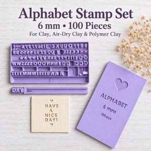 Pode incluir: Um conjunto de 100 carimbos do alfabeto em roxo claro, contendo letras, números e símbolos individuais numa bandeja, uma barra de suporte, um cartão retangular roxo com o texto ALPHABET 6 mm 100 pcs e um azulejo de argila quadrado.