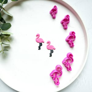 May include: Pink flamingo shaped cookie cutters on a white plate.