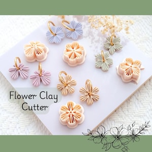 Peut inclure: Diverses découpoirs à fleurs en argile et boucles d'oreilles assorties dans des tons pastel, rose, beige et bleu clair. Les boucles d'oreilles ont des cerceaux dorés. Le texte "Flower Clay Cutter" est affiché.