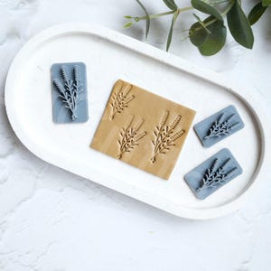 May include: Four blue rubber stamps with a floral design, one larger stamp with multiple floral designs, and a wooden block with the same floral design. The stamps are on a white surface.