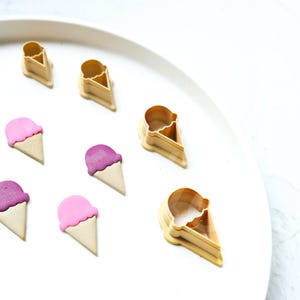 Könnte beinhalten: Ein Set mit sechs Eiswaffel-Ausstechern, zwei rosa und vier lila, sowie zwei zusätzlichen goldenen Eiswaffel-Ausstechern.